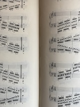 A page from a musical score with a series of staffs displaying treble and bass clefs, filled with an arrangement of musical notes and symbols. The notes vary in pitch and rhythm, indicating a complex composition. The sheet music is open to two pages, visible on both the left and right sides.