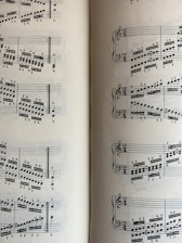 A page from a musical score with a series of staffs displaying treble and bass clefs, filled with an arrangement of musical notes and symbols. The notes vary in pitch and rhythm, indicating a complex composition. The sheet music is open to two pages, visible on both the left and right sides.