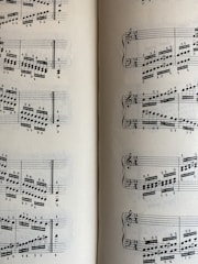 A page from a musical score with a series of staffs displaying treble and bass clefs, filled with an arrangement of musical notes and symbols. The notes vary in pitch and rhythm, indicating a complex composition. The sheet music is open to two pages, visible on both the left and right sides.