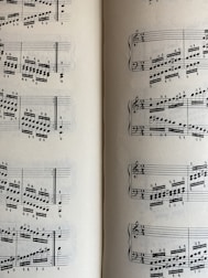 A page from a musical score with a series of staffs displaying treble and bass clefs, filled with an arrangement of musical notes and symbols. The notes vary in pitch and rhythm, indicating a complex composition. The sheet music is open to two pages, visible on both the left and right sides.