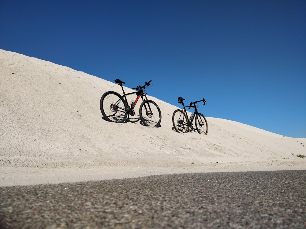 낮에 하얀 모래 위에서 자전거를 타는 남자 2명