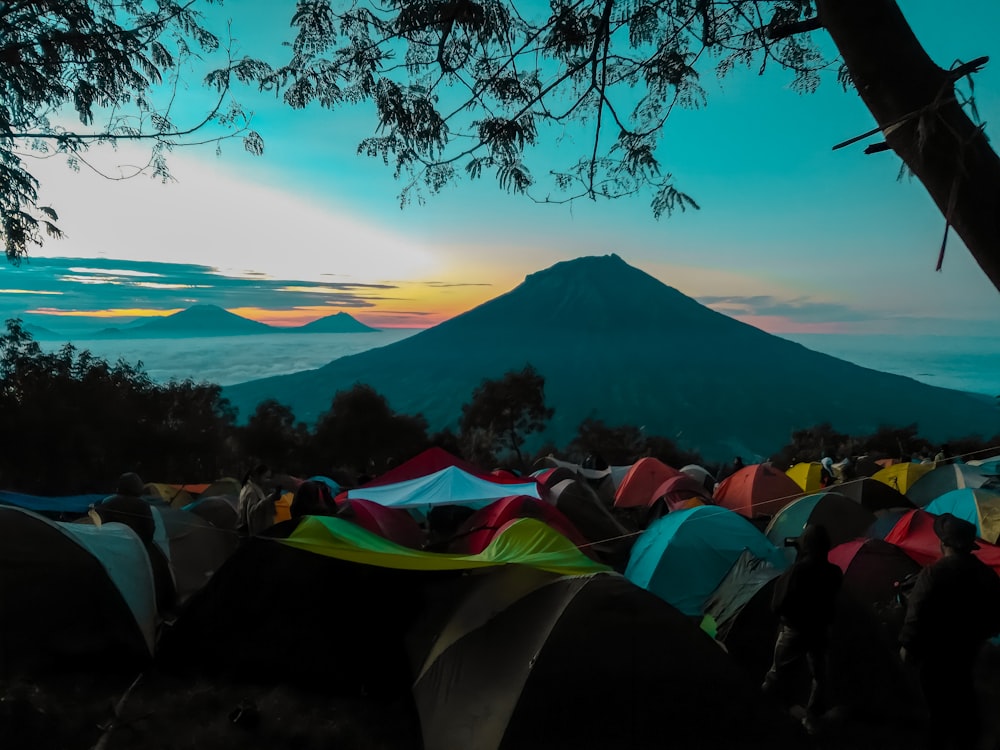 tent on green grass field near mountain under blue sky during daytime