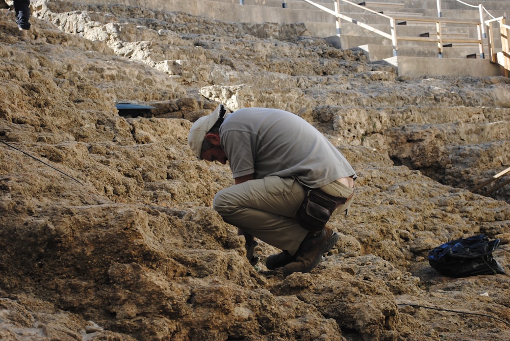 Homme en veste grise et pantalon marron assis sur Brown Rock pendant la journée