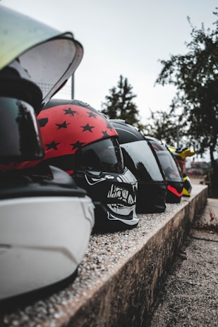 A row of colorful motorcycle helmets displayed outdoors on a sunny day