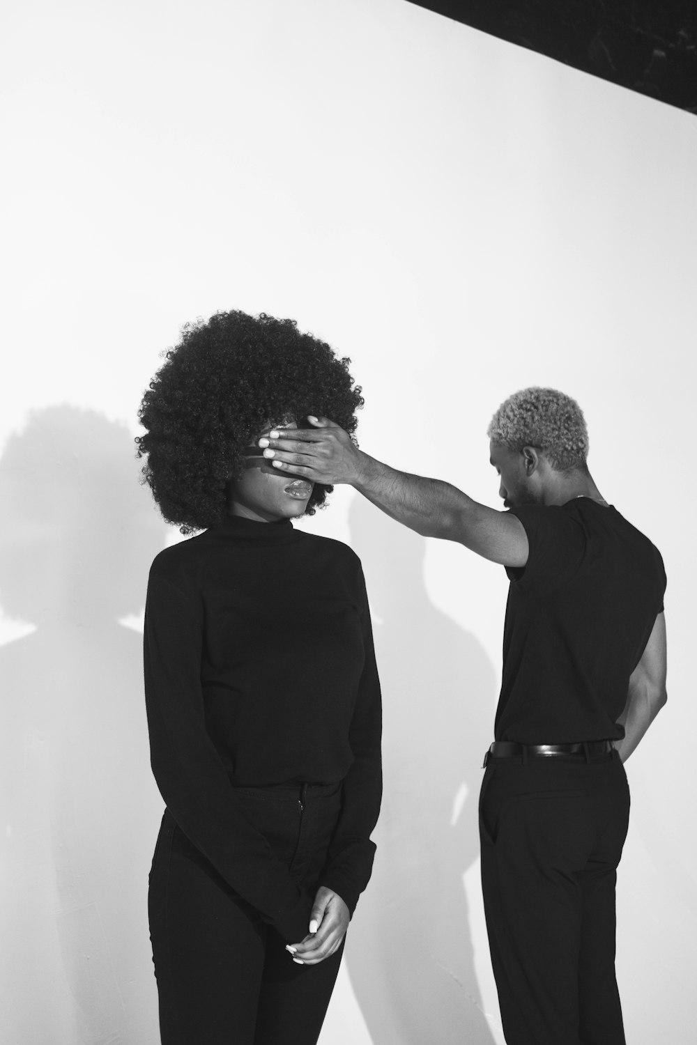 man in black shirt holding womans hair