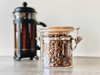 Bocal en verre transparent avec du café en grains à l'intérieur