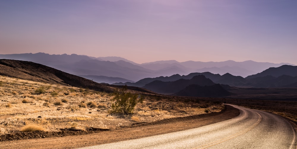 brown dirt road near brown mountains during daytime