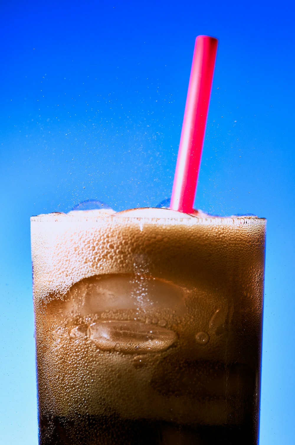 clear drinking glass with ice and red straw