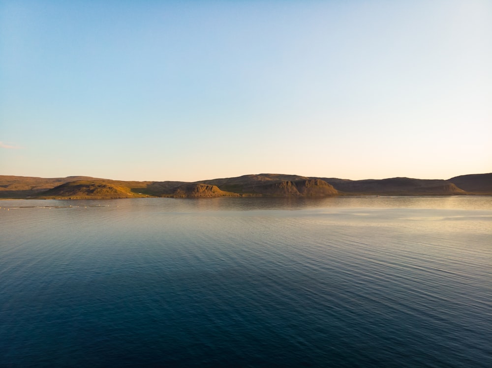 brown and green mountain beside body of water during daytime