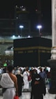 Pilgrims gathering near the Kaaba during sunset, with hotel buildings in the background.