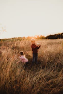 Children playing in a sunlit field with terracotta hues in the background.