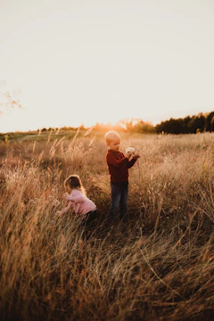Children playing in a sunlit field with terracotta hues in the background.