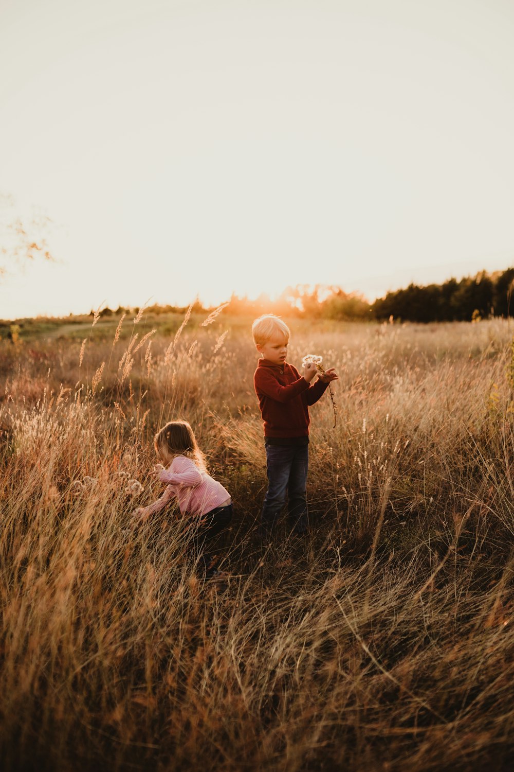 man in black jacket carrying girl in pink jacket on brown grass field during daytime