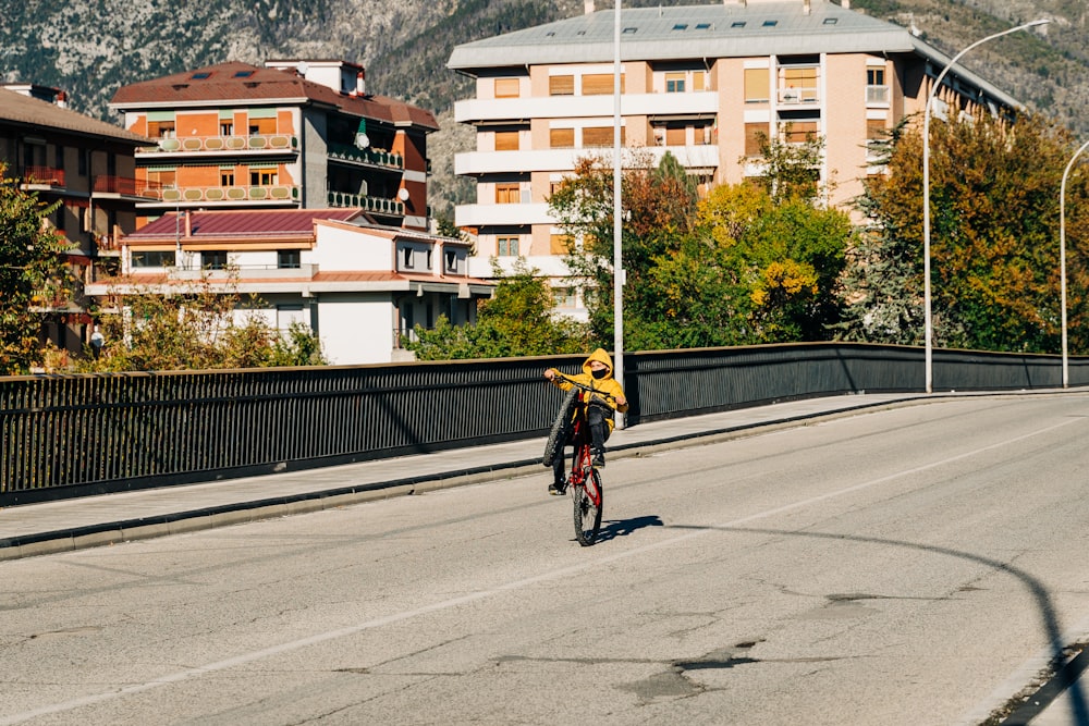 昼間、道路を自転車で走る黄色いジャケットを着た男性
