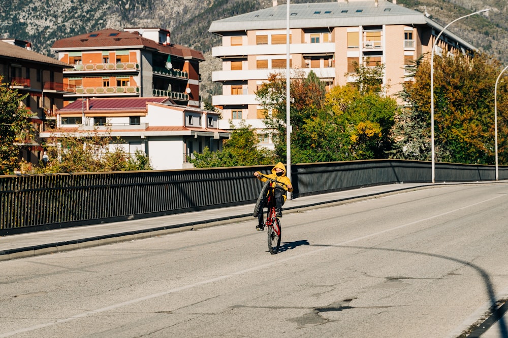 Hombre en chaqueta amarilla montando en bicicleta en la carretera durante el día