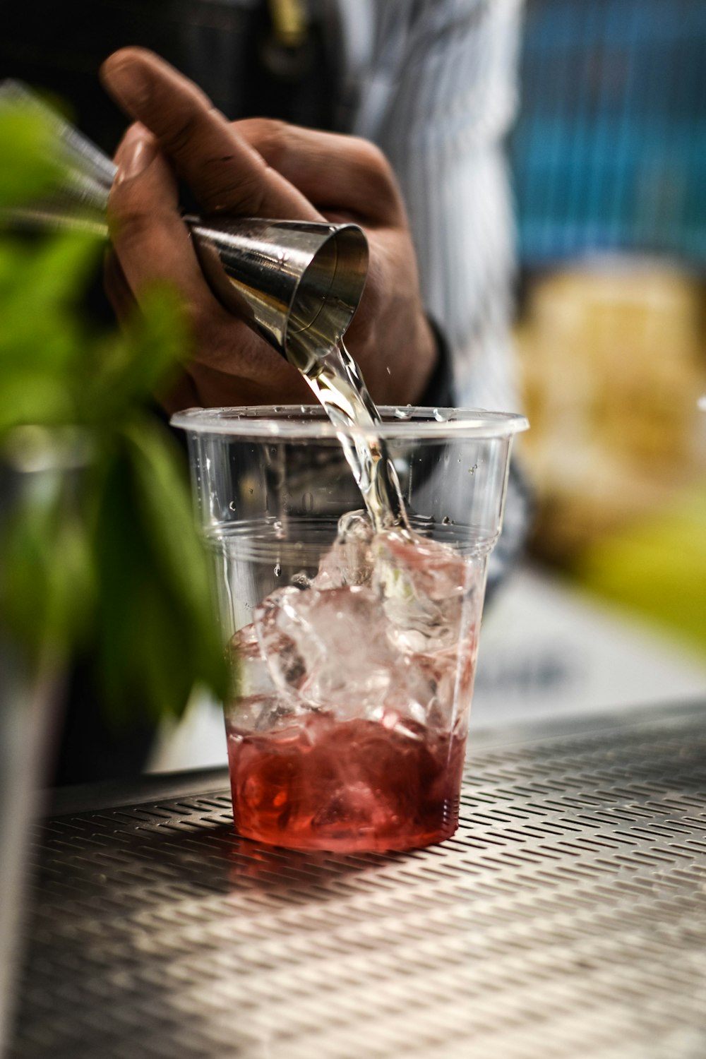 person pouring red liquid on clear drinking glass