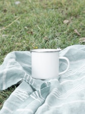 white ceramic mug on gray and white textile