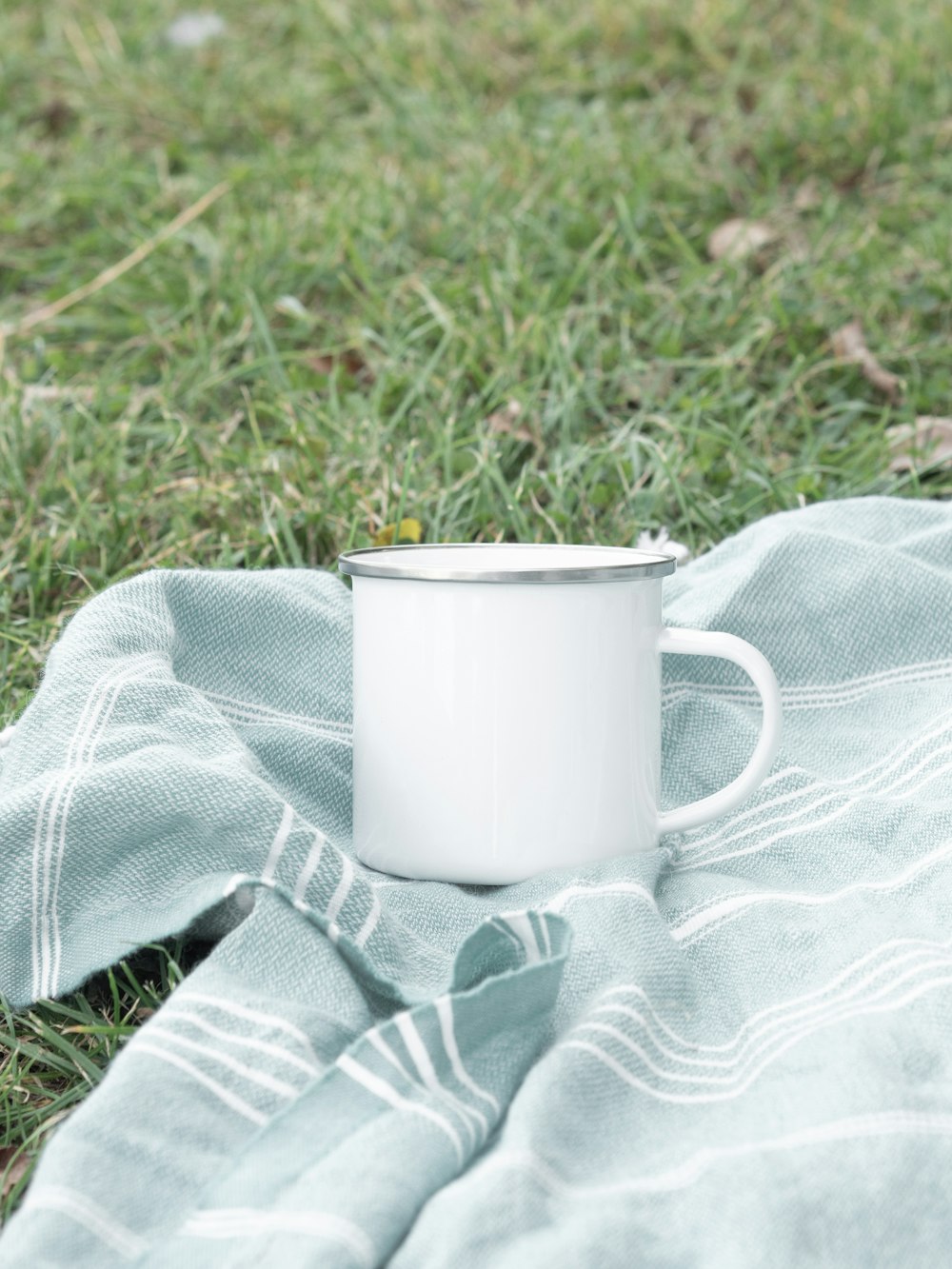 Taza de cerámica blanca sobre textil gris y blanco