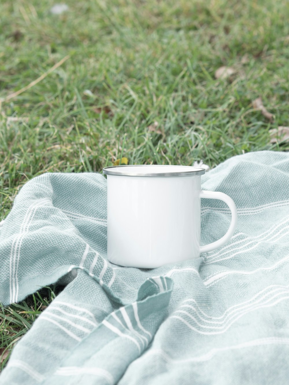 white ceramic mug on gray and white textile