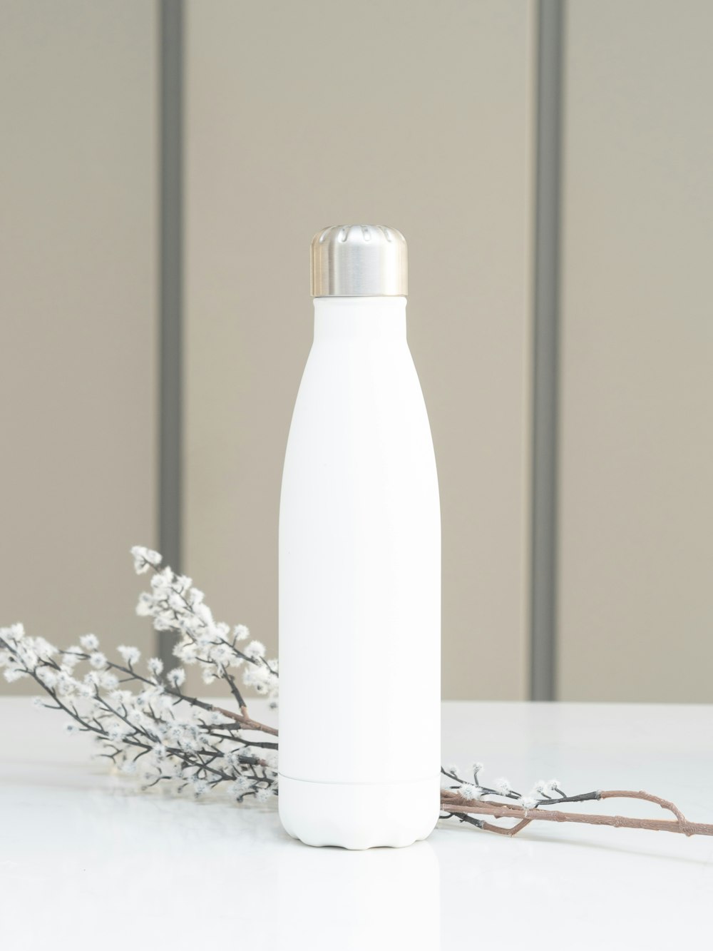 Botella blanca sobre mesa blanca