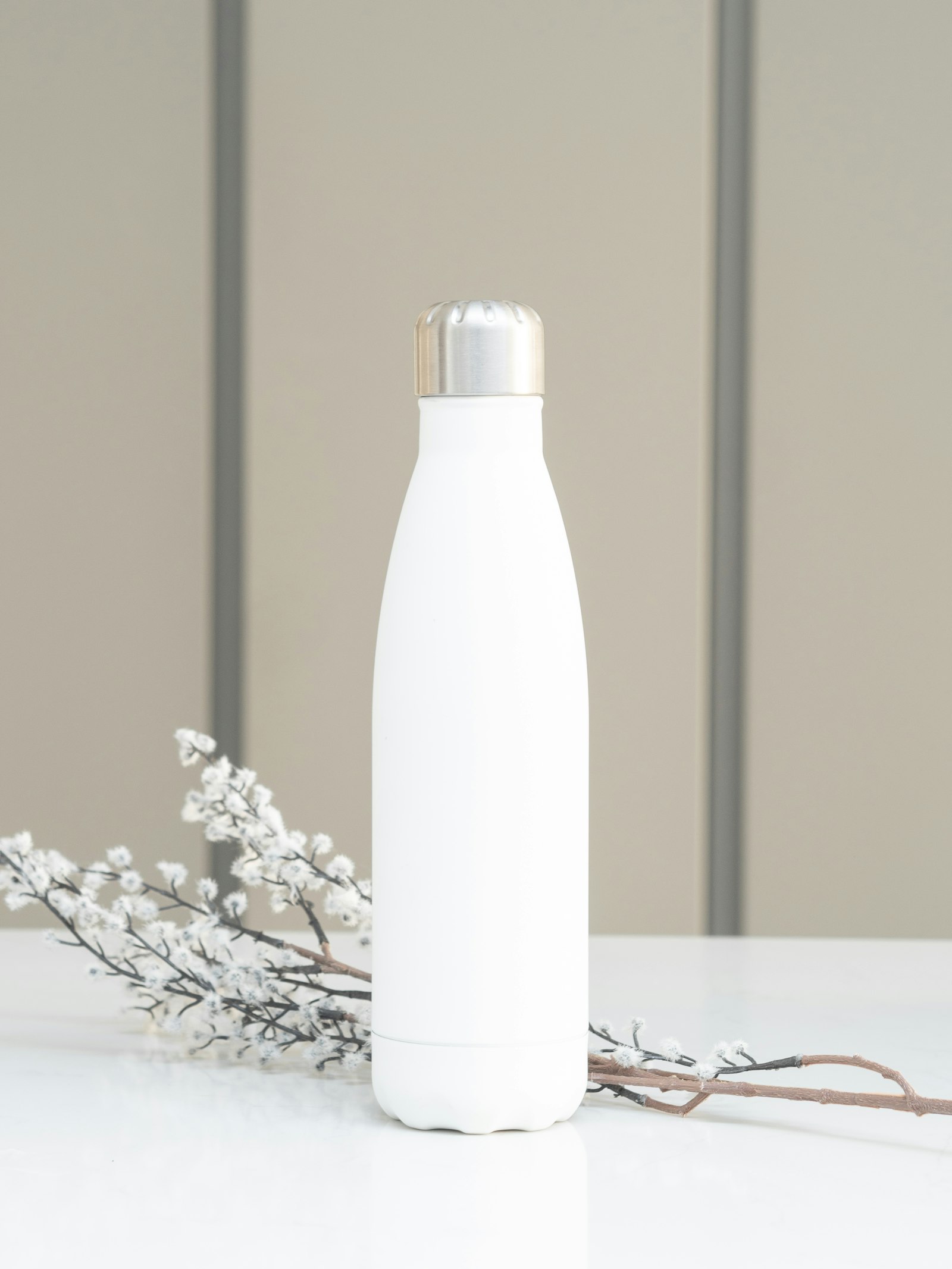 Une gourde isotherme blanche près de brindilles fleuries