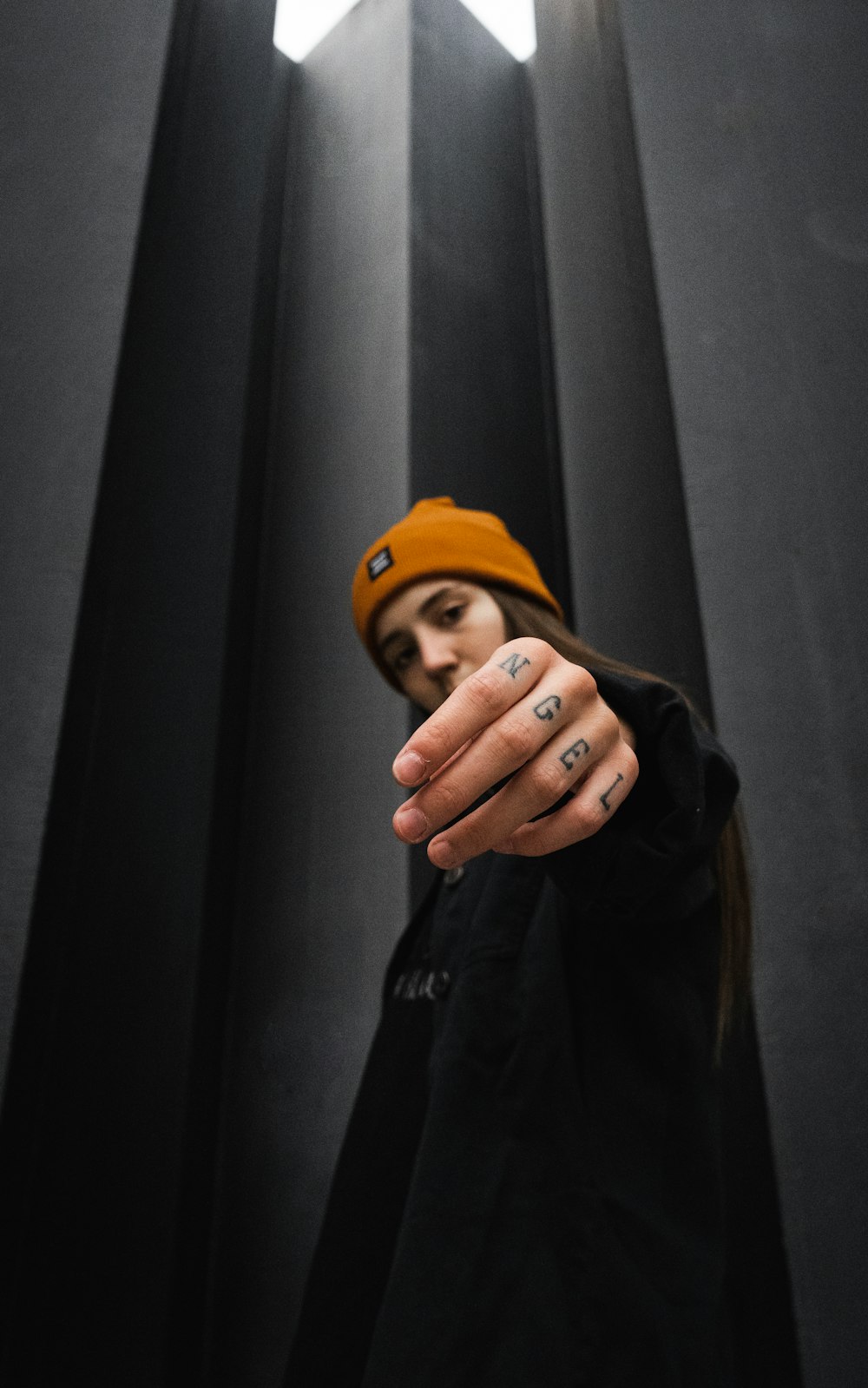 man in black leather jacket wearing orange knit cap covering his face