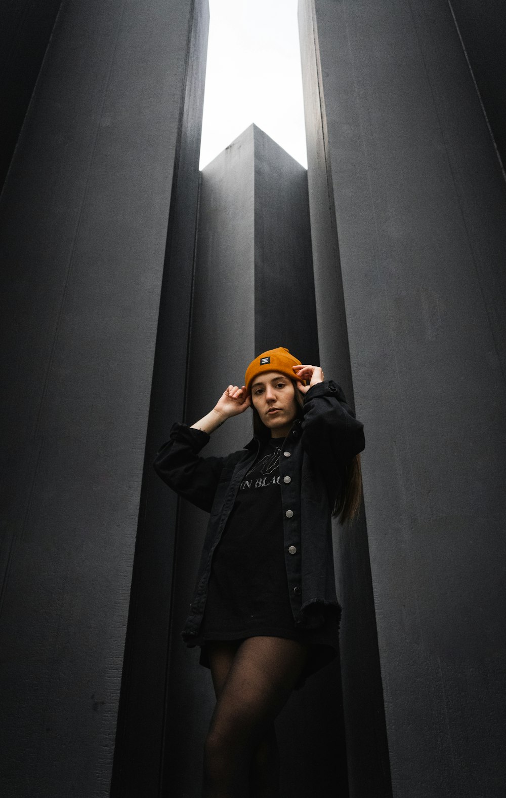 woman in black coat covering her face with her orange hijab