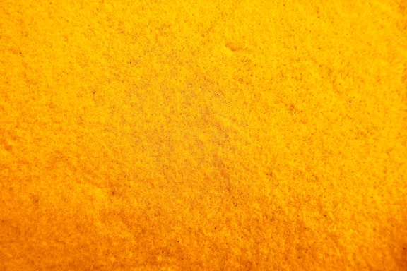 A textured surface with a rich yellow hue, exhibiting a uniform pattern resembling a close-up of a sponge or fabric.