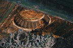 Intricate wooden carvings with a focus on a serene Buddha statue embedded in a detailed, ornate ceiling. Rich textures and patterns are highlighted, showcasing a fusion of cultural artistry and spirituality.