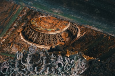 Intricate wooden carvings with a focus on a serene Buddha statue embedded in a detailed, ornate ceiling. Rich textures and patterns are highlighted, showcasing a fusion of cultural artistry and spirituality.