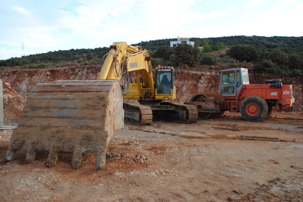 yellow and black excavator near yellow heavy equipment
