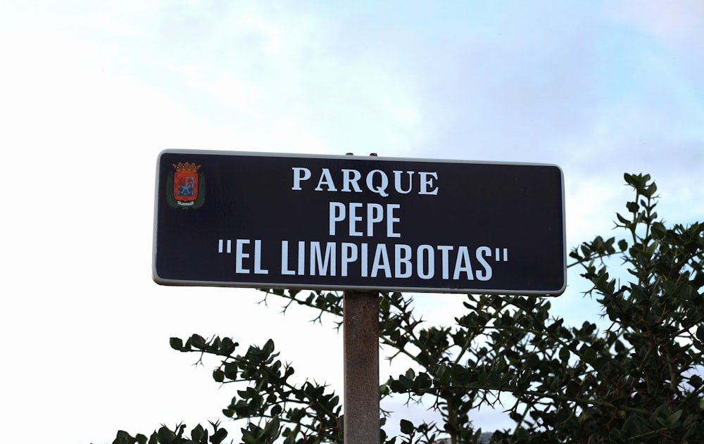 a black street sign with spanish writing on it