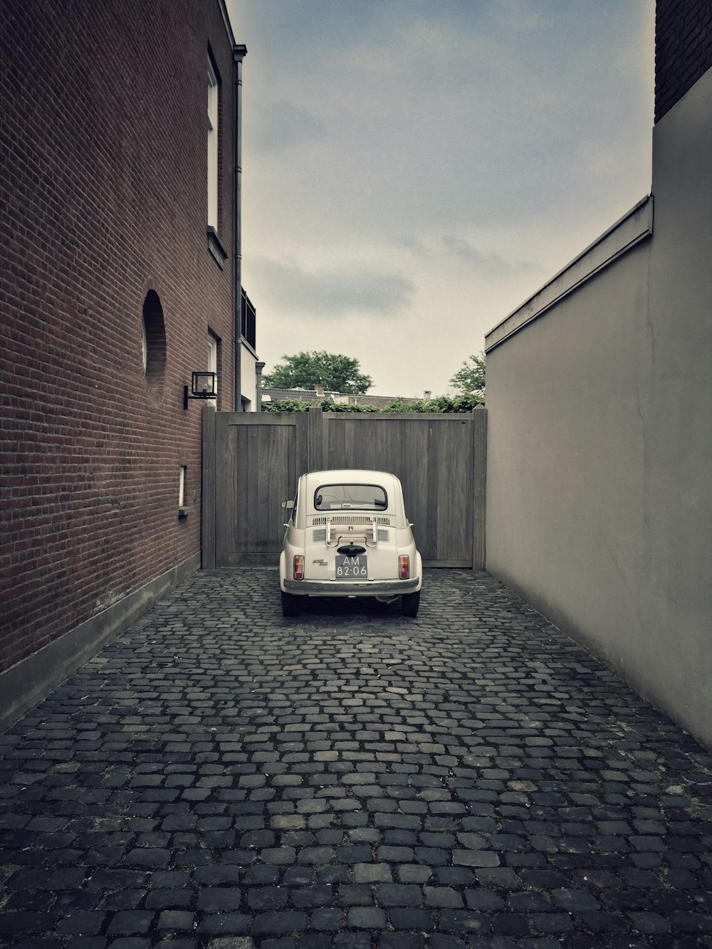 white car parked beside brown brick building during daytime