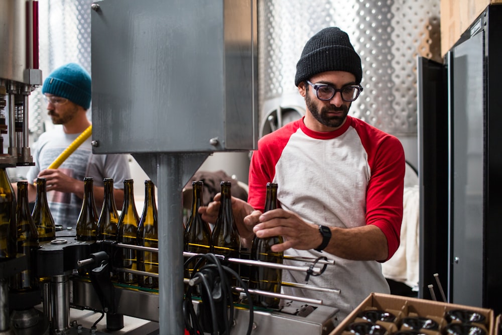 man in red and white long sleeve shirt wearing black knit cap holding black bottle