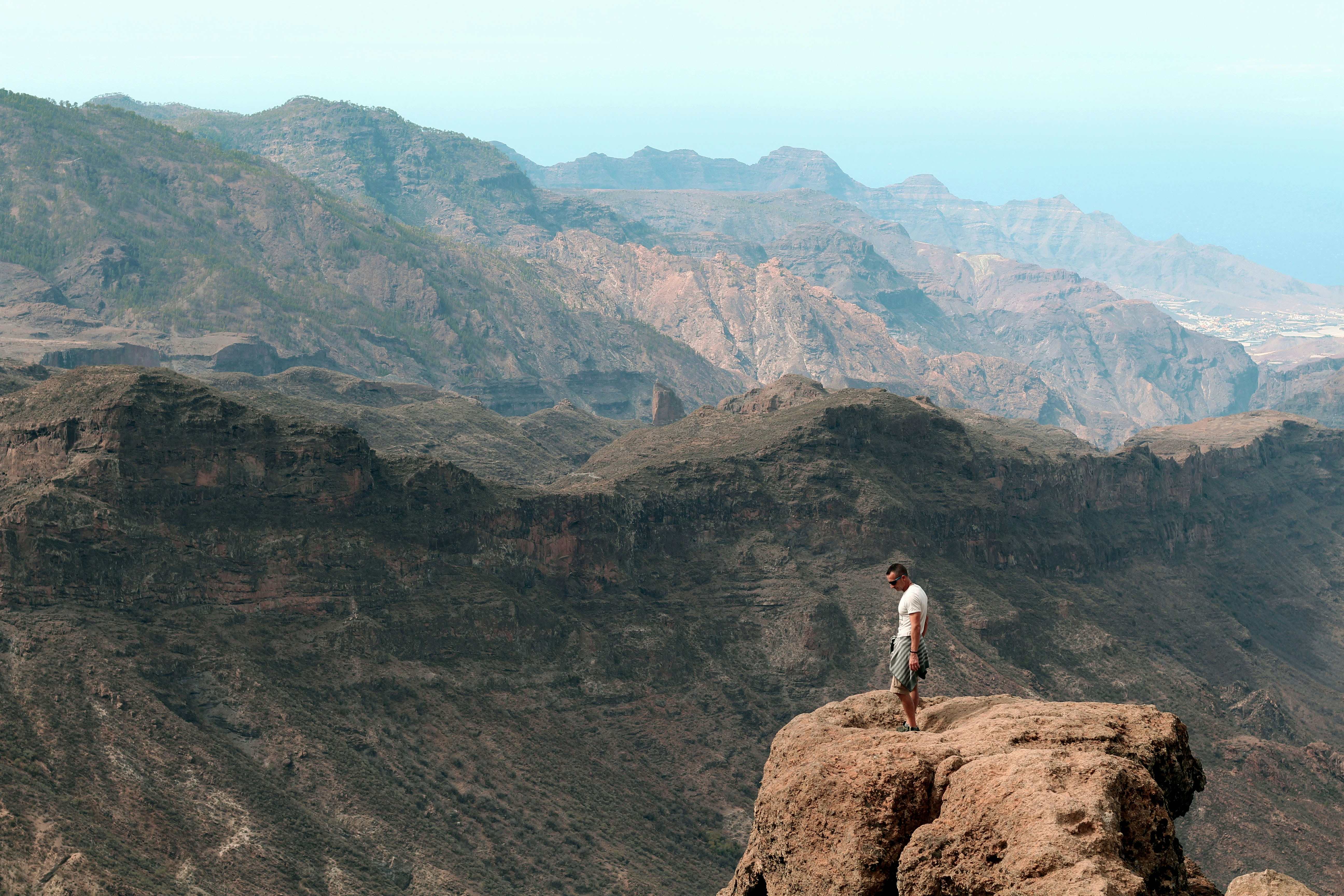 man in white shirt standing on brown rock mountain during daytime