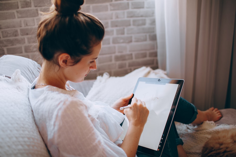 woman in white shirt holding white tablet computer