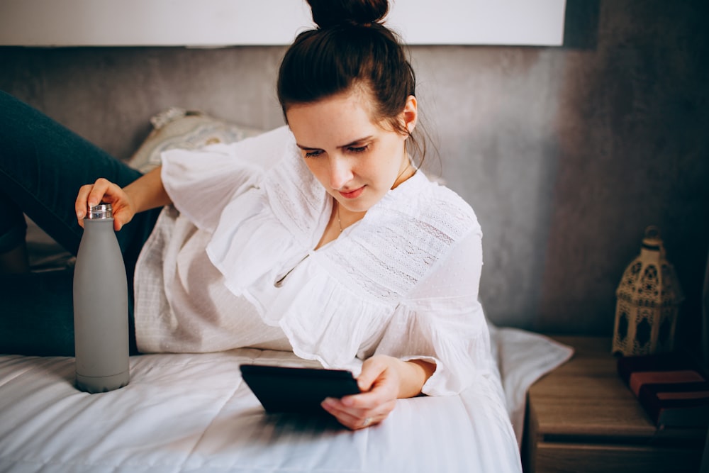 woman in white long sleeve shirt sitting on bed