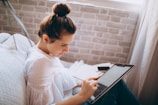 woman in white shirt holding black and silver laptop computer