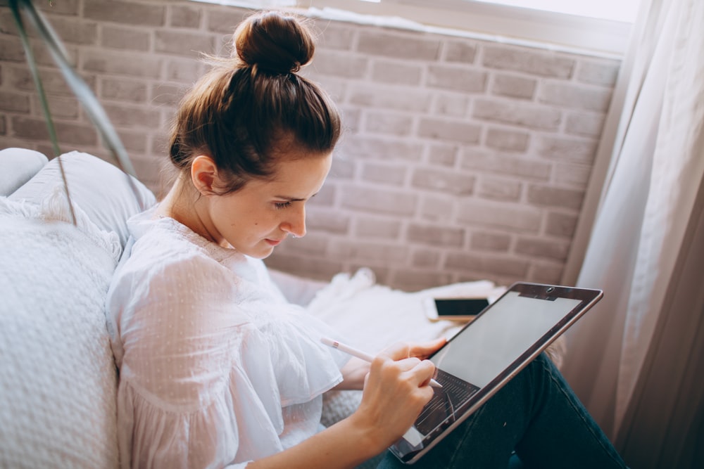 donna in camicia bianca che tiene il computer portatile nero e argento