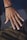 A close-up of a hand with a bracelet made of black beads and a ring featuring an infinity symbol. The skin tone is warm and the nails are neatly trimmed. The background is blurred, highlighting the hand as the focal point.