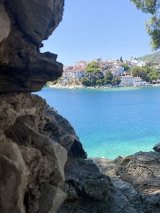 A scenic seaside spot with pastel-colored buildings and olive trees under a soft blue sky.