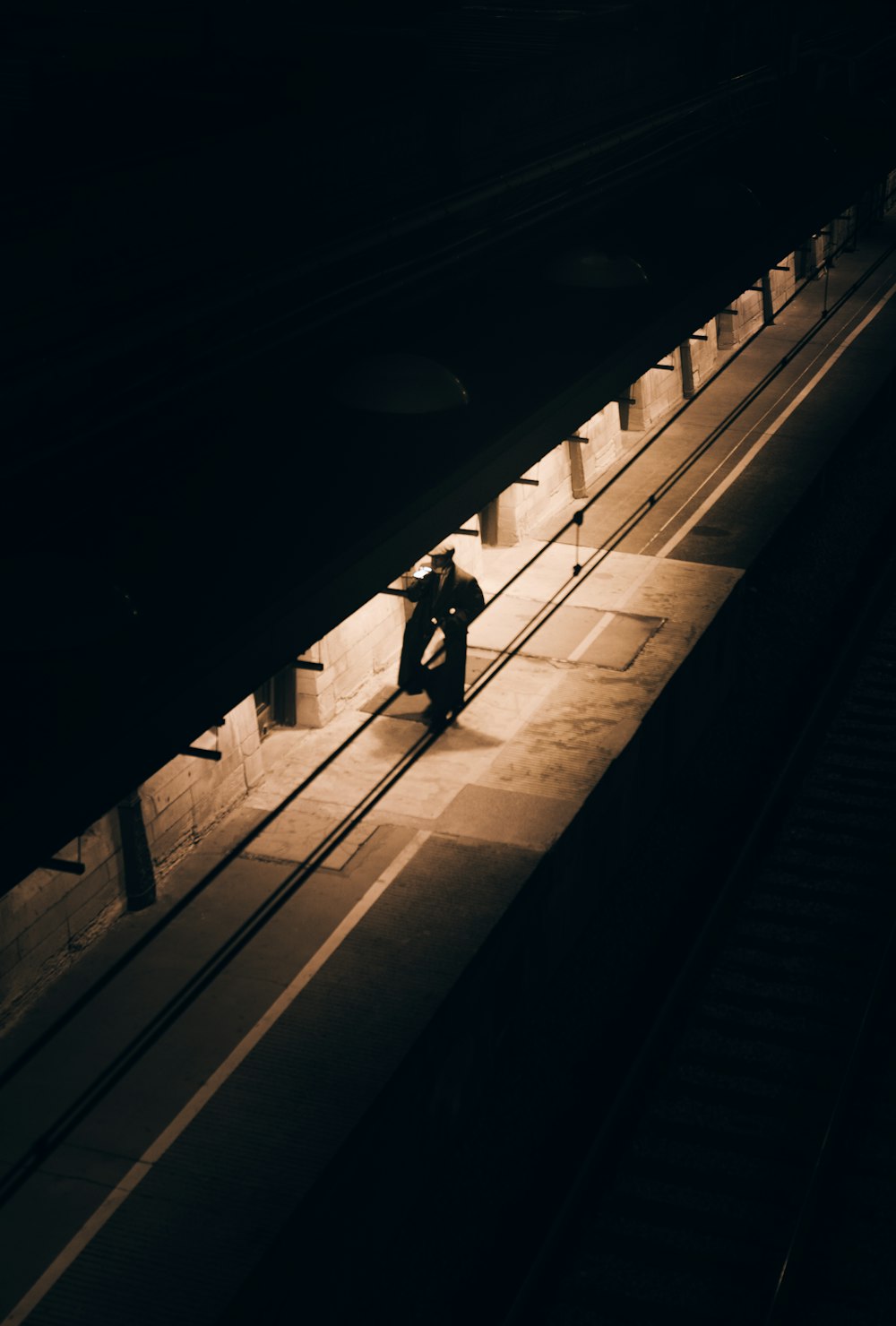 man in black jacket walking on sidewalk during night time