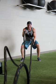 man in black tank top and blue denim shorts sitting on black metal bar