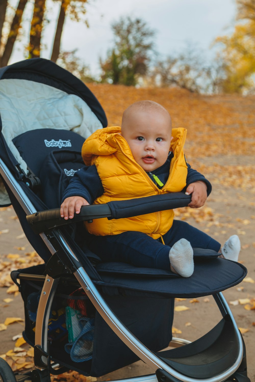 child in yellow hoodie sitting on stroller