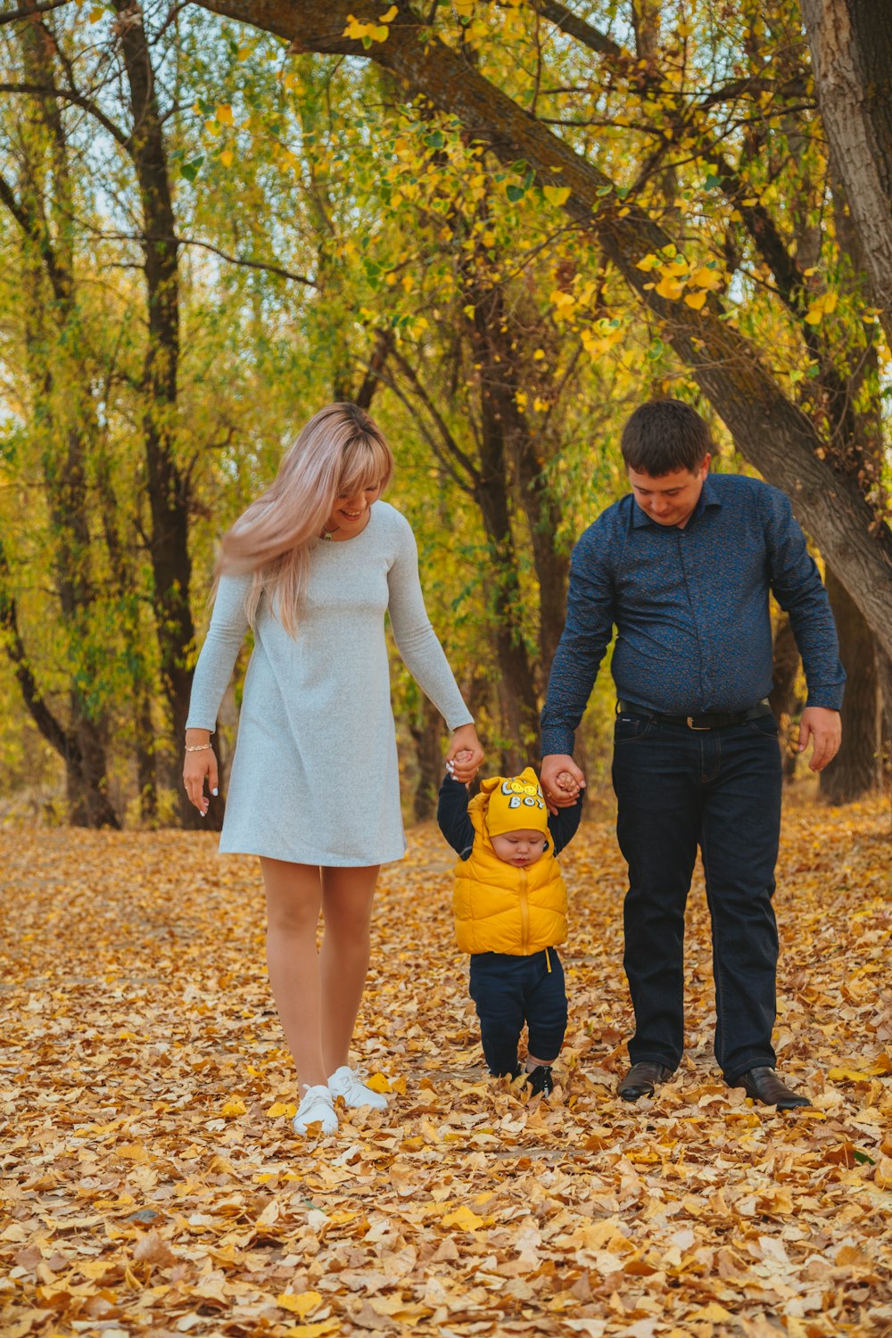 man and woman holding hands while walking on brown dried leaves on forest during daytime