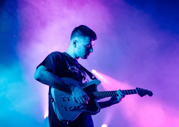 man in black crew neck t-shirt playing electric guitar