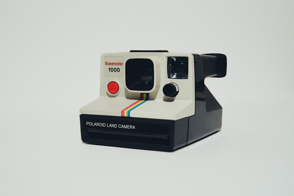 Cámara instantánea Polaroid blanca sobre superficie blanca