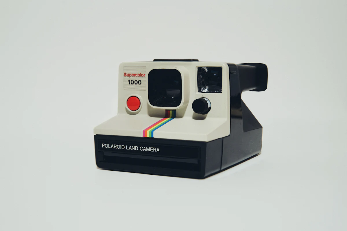 Instant camera resting on a table beside a stack of developed prints