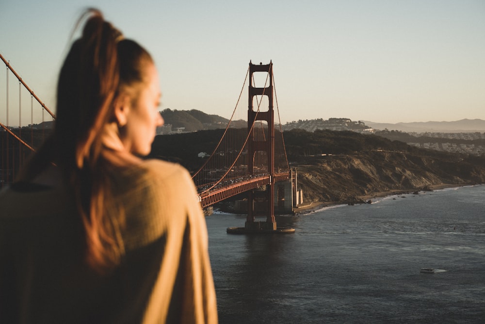 woman in brown jacket standing on bridge during daytime