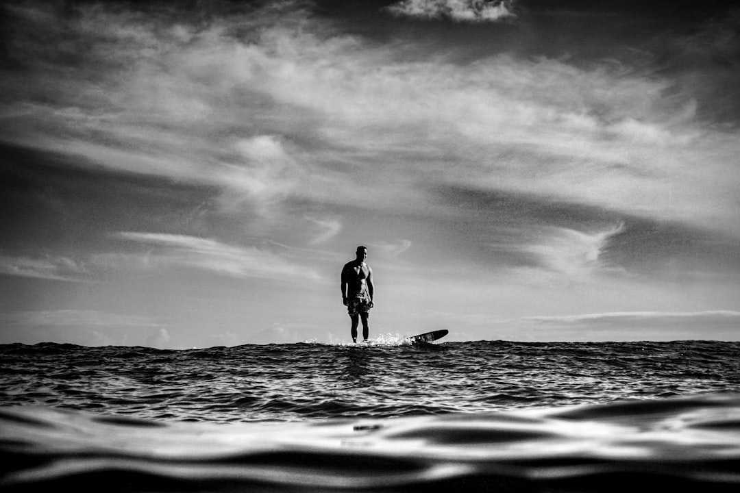 silhouette of man standing on surfboard on sea water